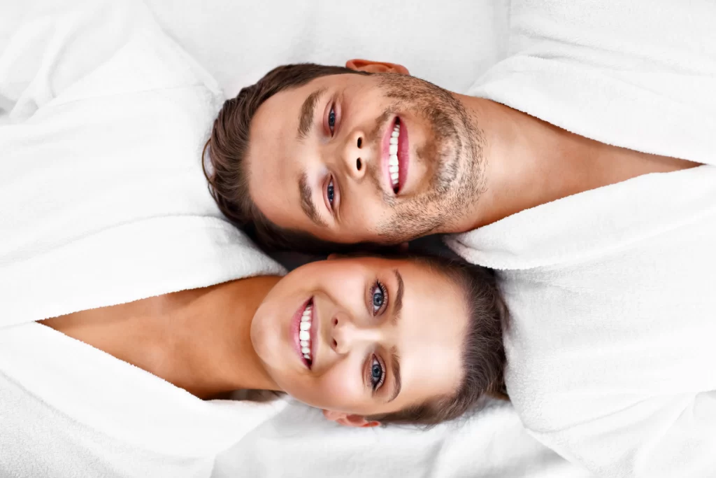 smiling couple in white robes relaxing together utc